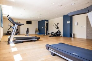 A gym with treadmills, stationary bikes, and exercise equipment. - Hôtel Le Bastia (Bastia)