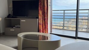A modern room with a large TV, a desk, and a view of the sea. - Hôtel Le Bastia (Bastia)
