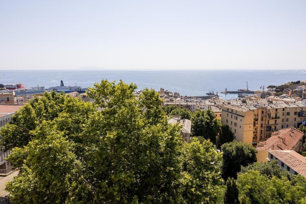 Un paisaje urbano costero con edificios, un puerto y una vista despejada del mar.