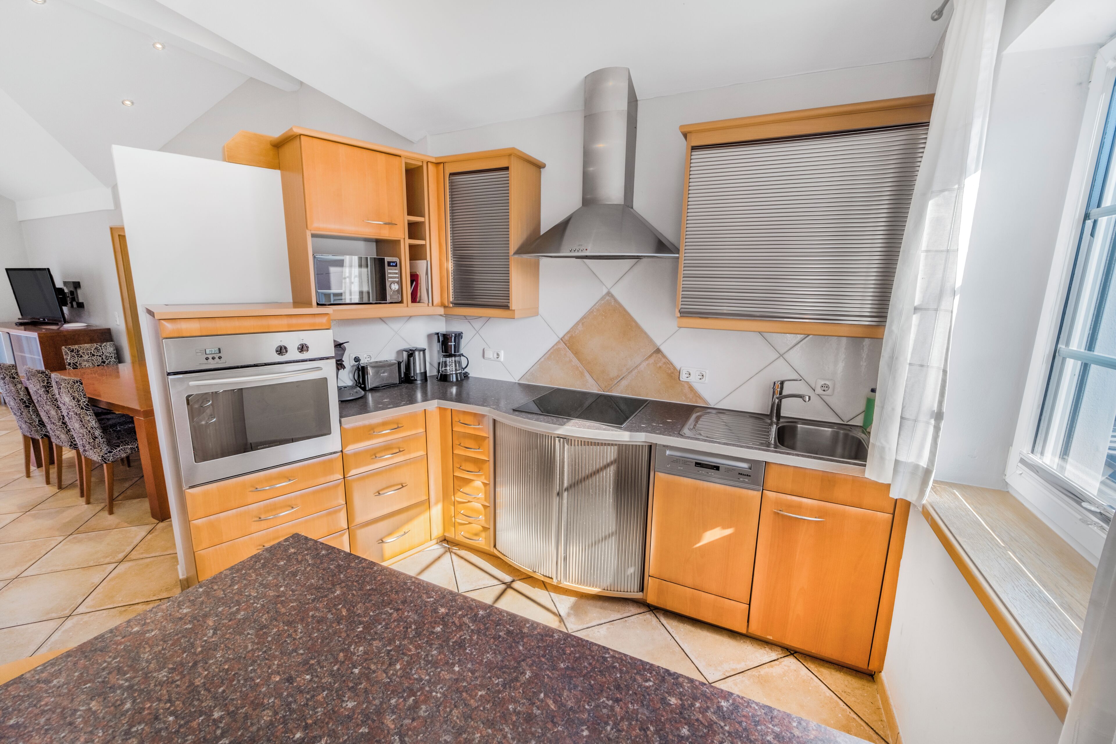 Een moderne keuken met inbouwapparatuur, houten kastjes en een groot raam.