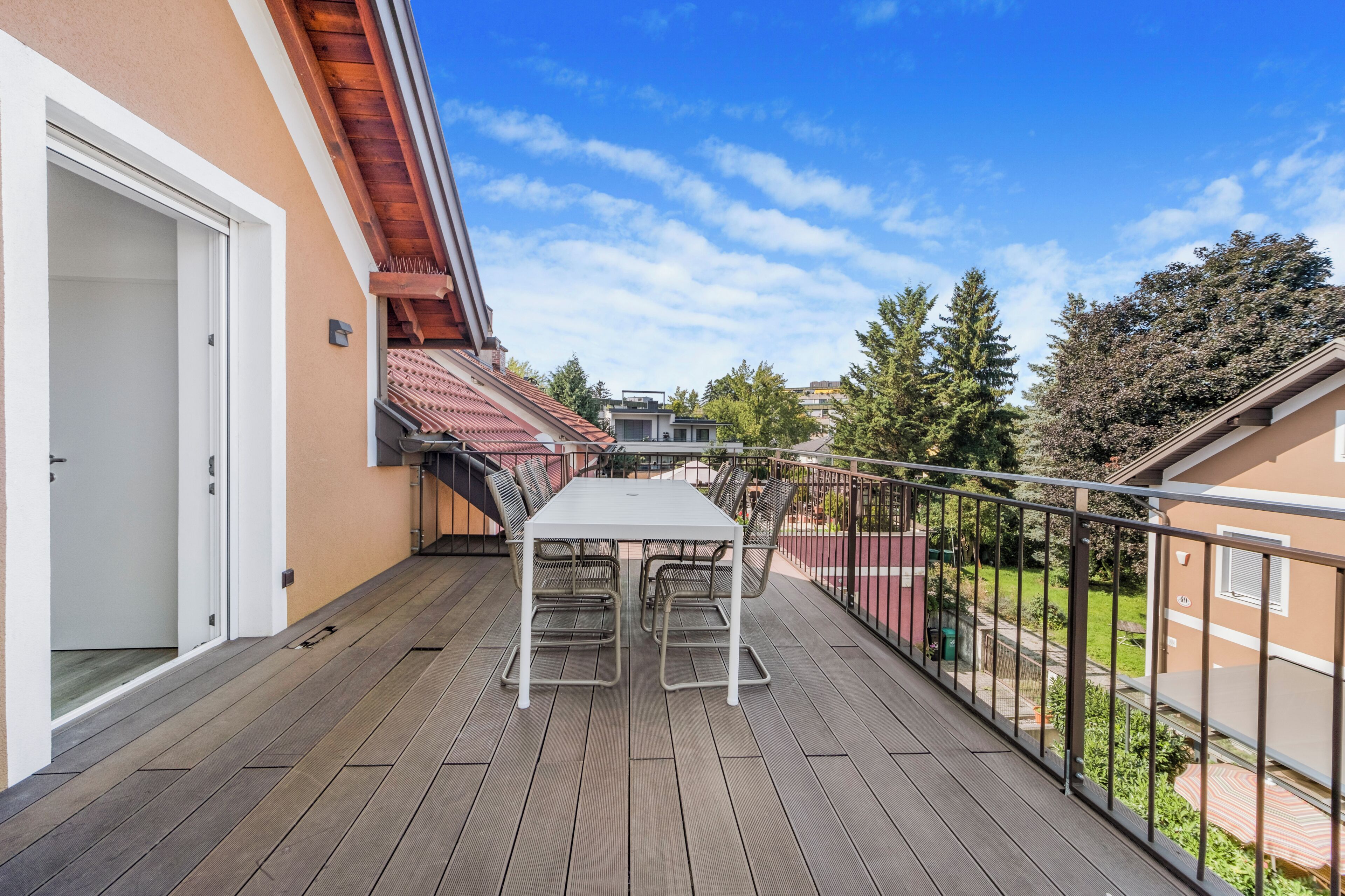 Ein Balkon mit Tisch und Stühlen, einer Tür und Blick ins Viertel.