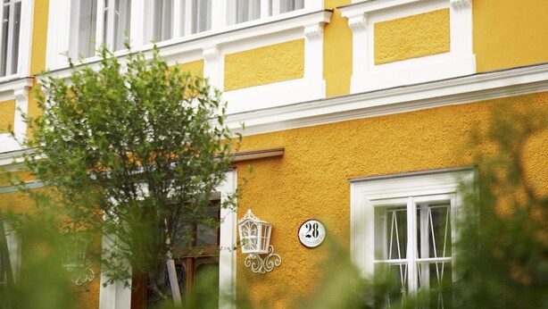 Un edificio amarillo con marcos de ventana blancos y un letrero con el número 28.