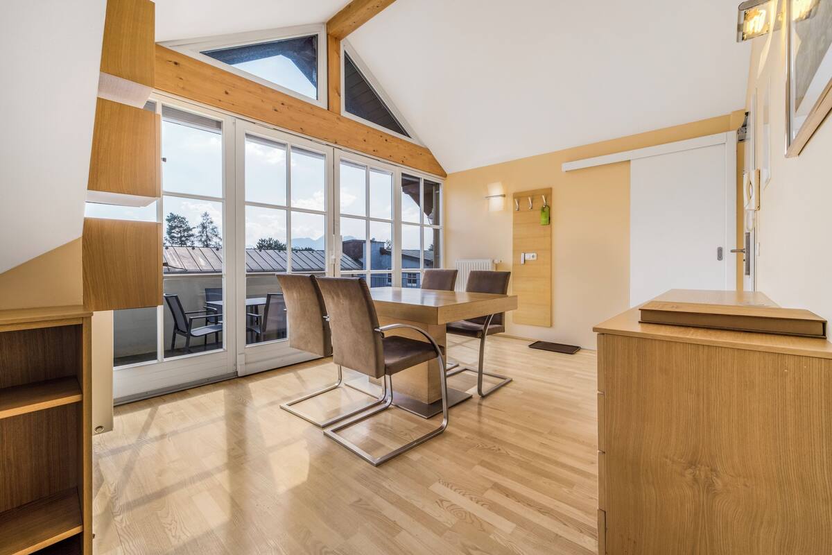 Una habitación moderna con suelo de madera, un ventanal grande y una mesa con sillas.