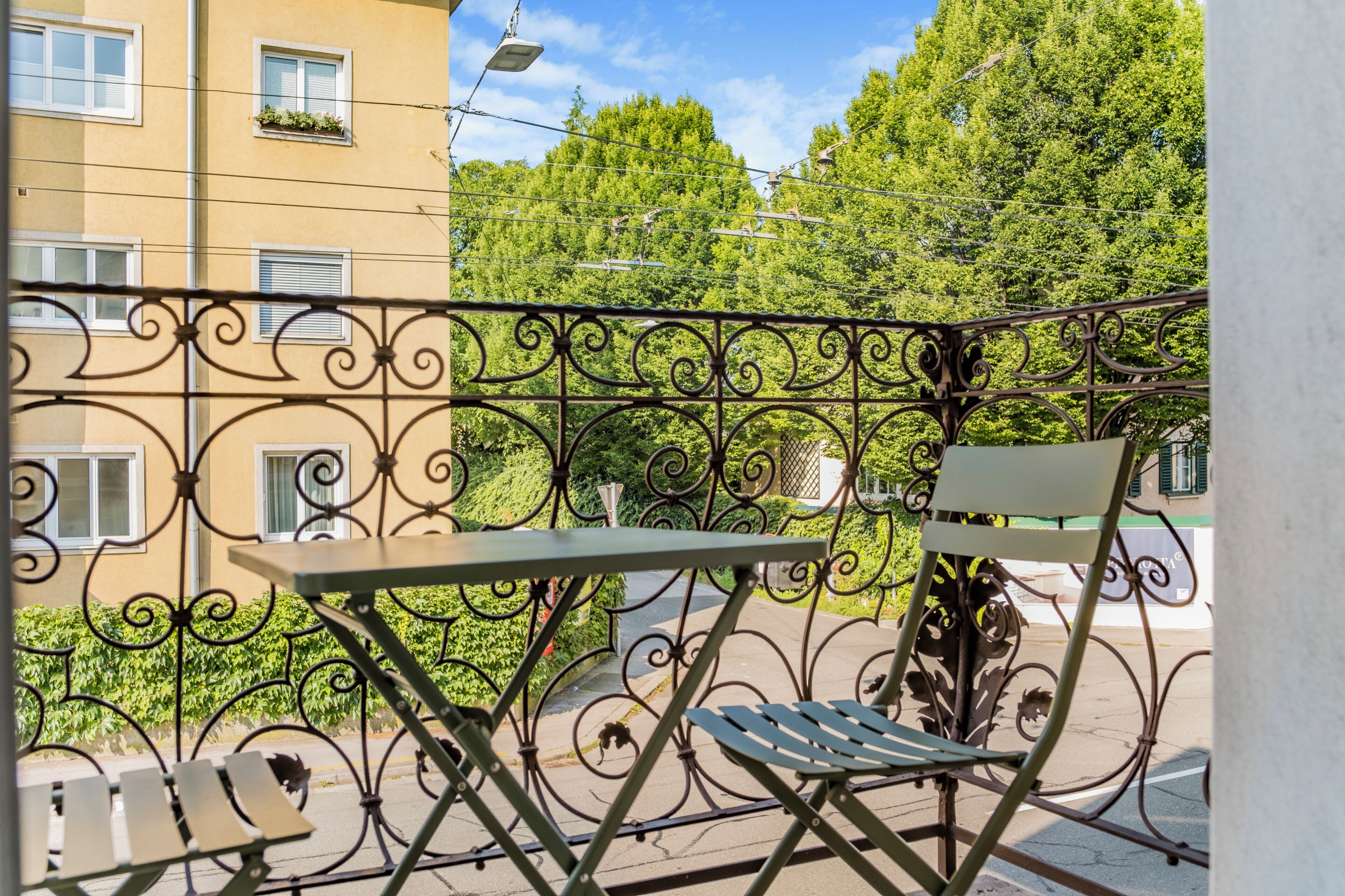 Ein Balkon mit Metallgeländer, einem Tisch und einem Stuhl.