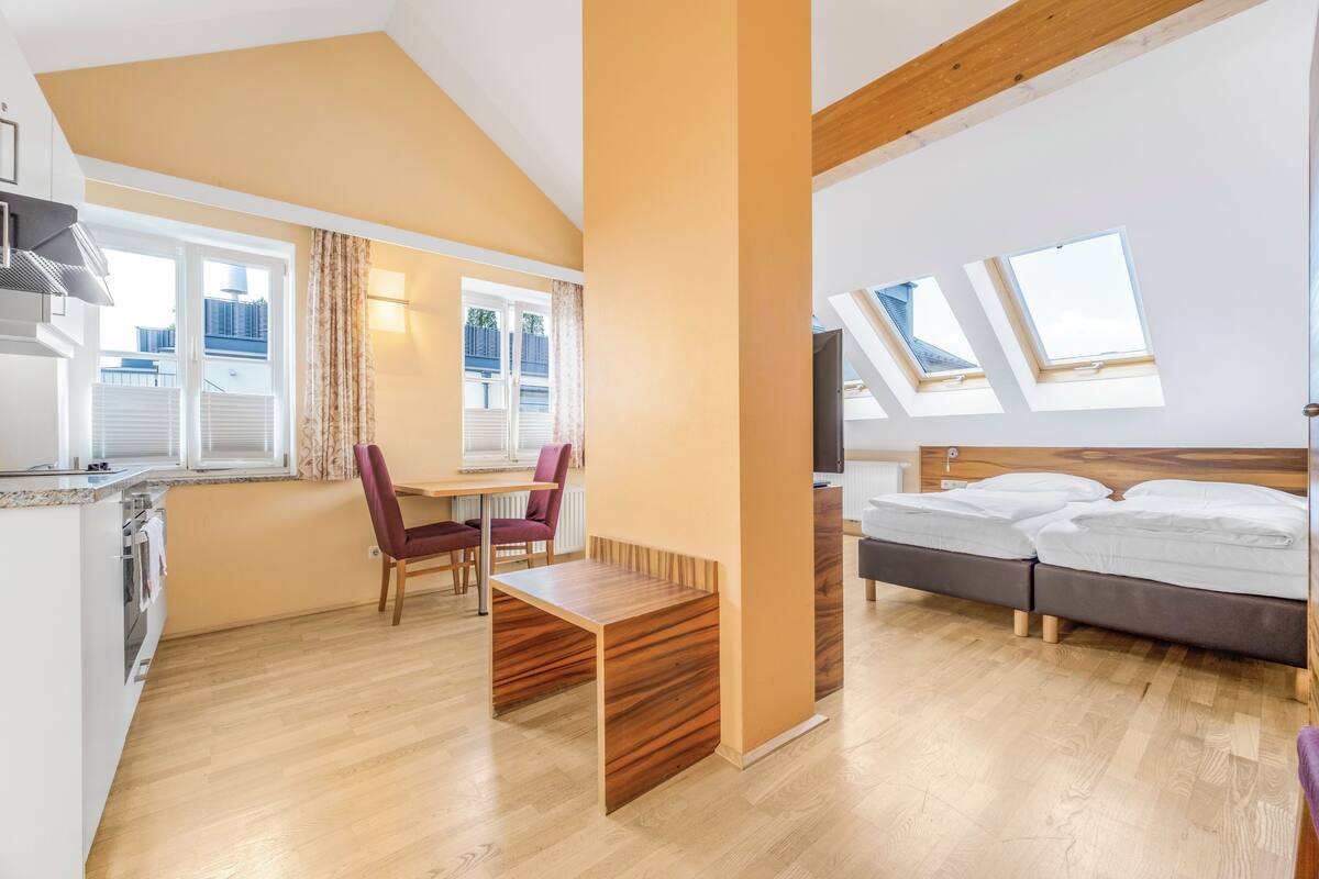 Una habitación moderna con una cama, una mesa de comedor y una zona de cocina.