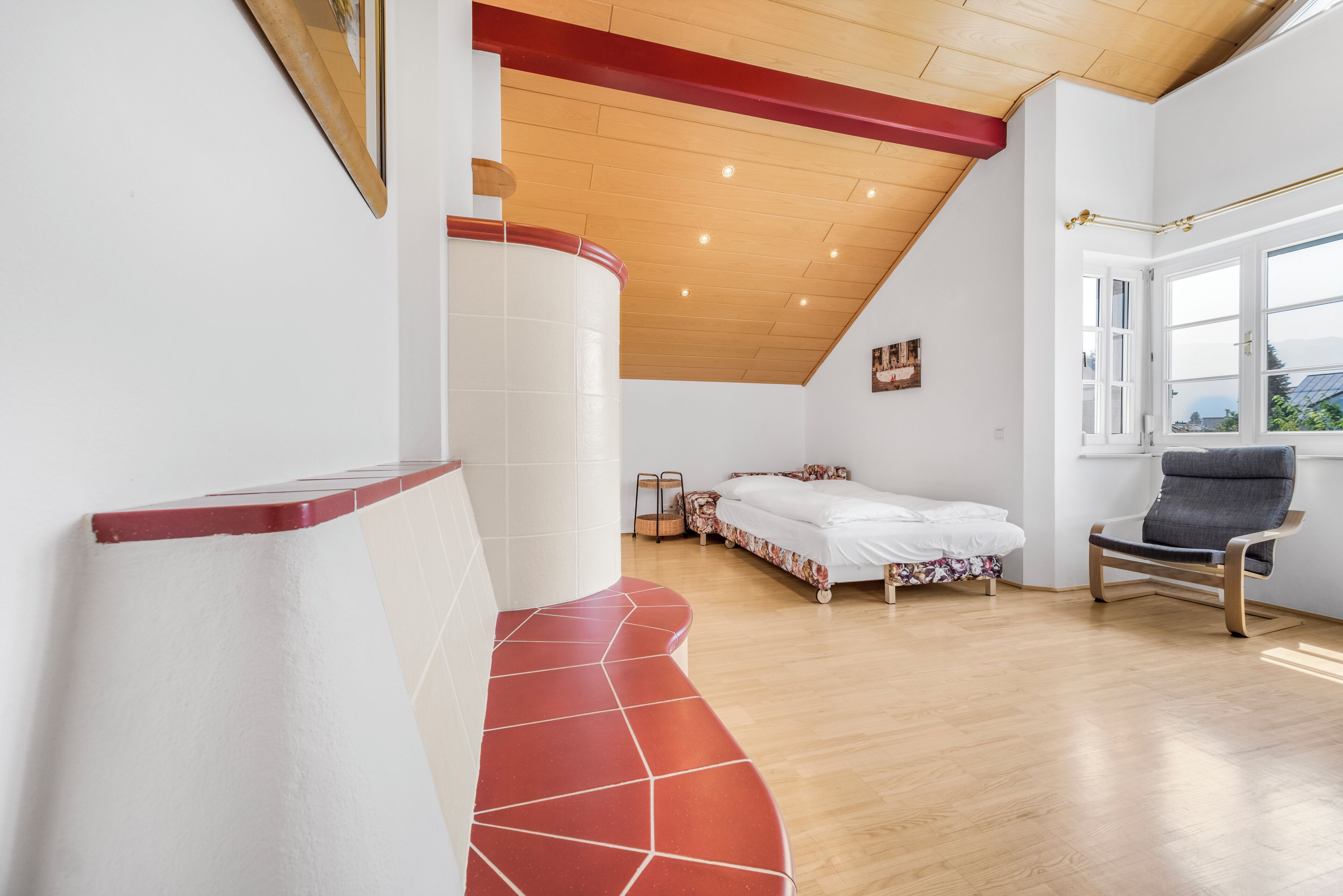 Ein Schlafzimmer mit einem Bett, einem Sessel, einem Fenster und einer gebogenen Bank.