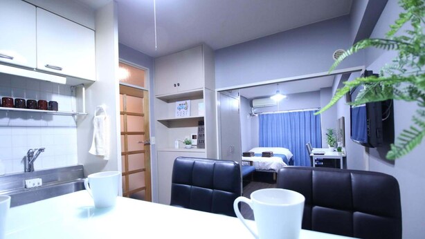 A compact hotel room with a kitchenette, a dining area with a table and chairs, a bed, and a TV mounted on the wall. - MG103 Cozy and clean room SHINAGAWA (品川区)