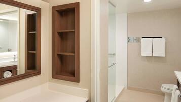 A modern bathroom with a large mirror, a wooden medicine cabinet, a glass shower enclosure, and a toilet with a towel rack.