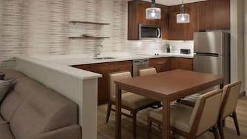 Una cocina moderna con una isla central, armarios de madera, un refrigerador de acero inoxidable e iluminación colgante.