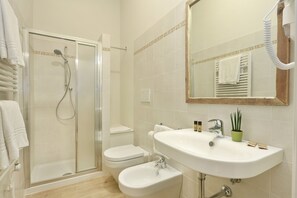 A modern bathroom with a glass-enclosed shower, a toilet, a sink, and a mirror. - Tornabuoni Boutique (Florence)