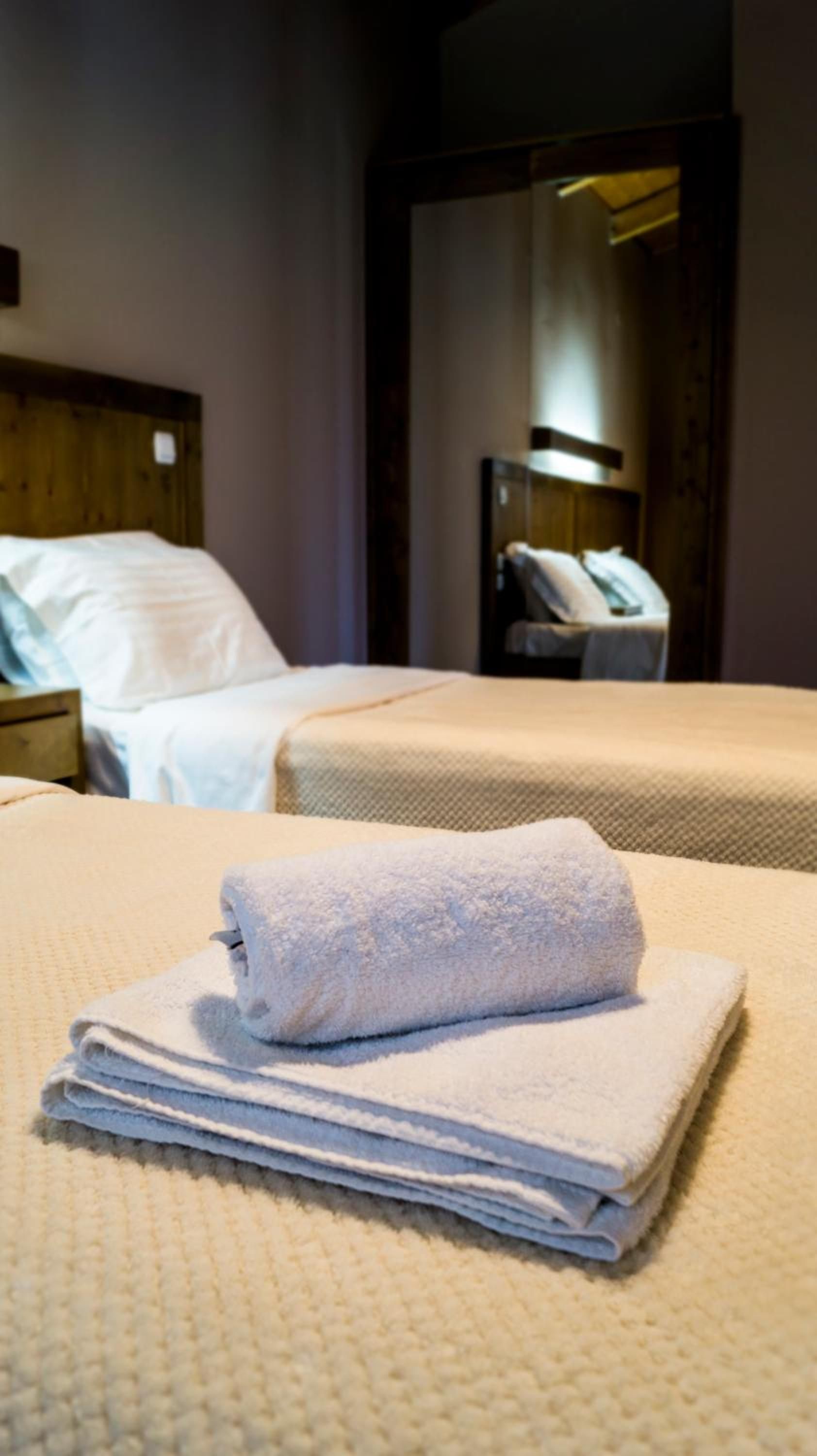 A hotel room with two beds, a wooden headboard, and a nightstand with a lamp.