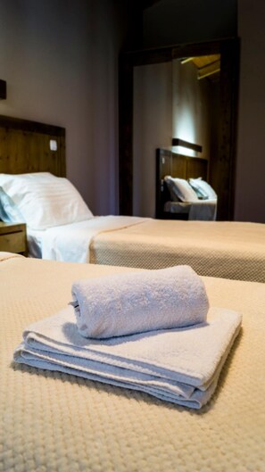 A hotel room with two beds, a wooden headboard, and a nightstand with a lamp. - Kedros Chalet (Nafpaktos)