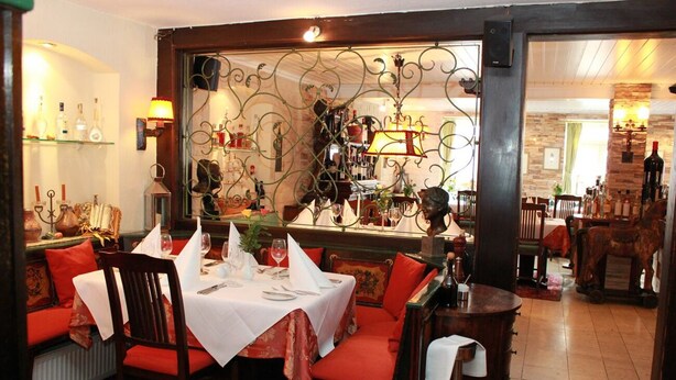 Un restaurant doté d’un espace salon accueillant, avec des banquettes rouges recouvertes de tissu et une table dressée pour le repas.