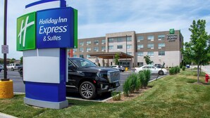 Un bâtiment Holiday Inn Express & Suites avec une enseigne, un VUS noir et un parking.