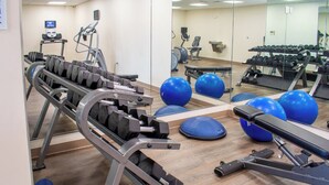 Une salle de sport équipée de matériel d’exercice, de ballons d’exercice bleus et d’un miroir qui reflète le matériel.