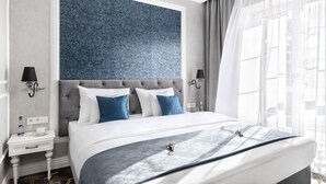 A modern hotel room with a large bed, a tufted headboard, and a decorative blue wall panel. - Merci Boutique Hotel (Kraków)