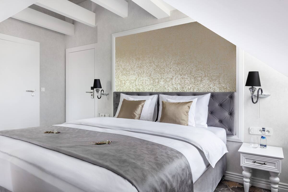 A modern bedroom with a large bed, a bedside table with a lamp, and a decorative headboard.