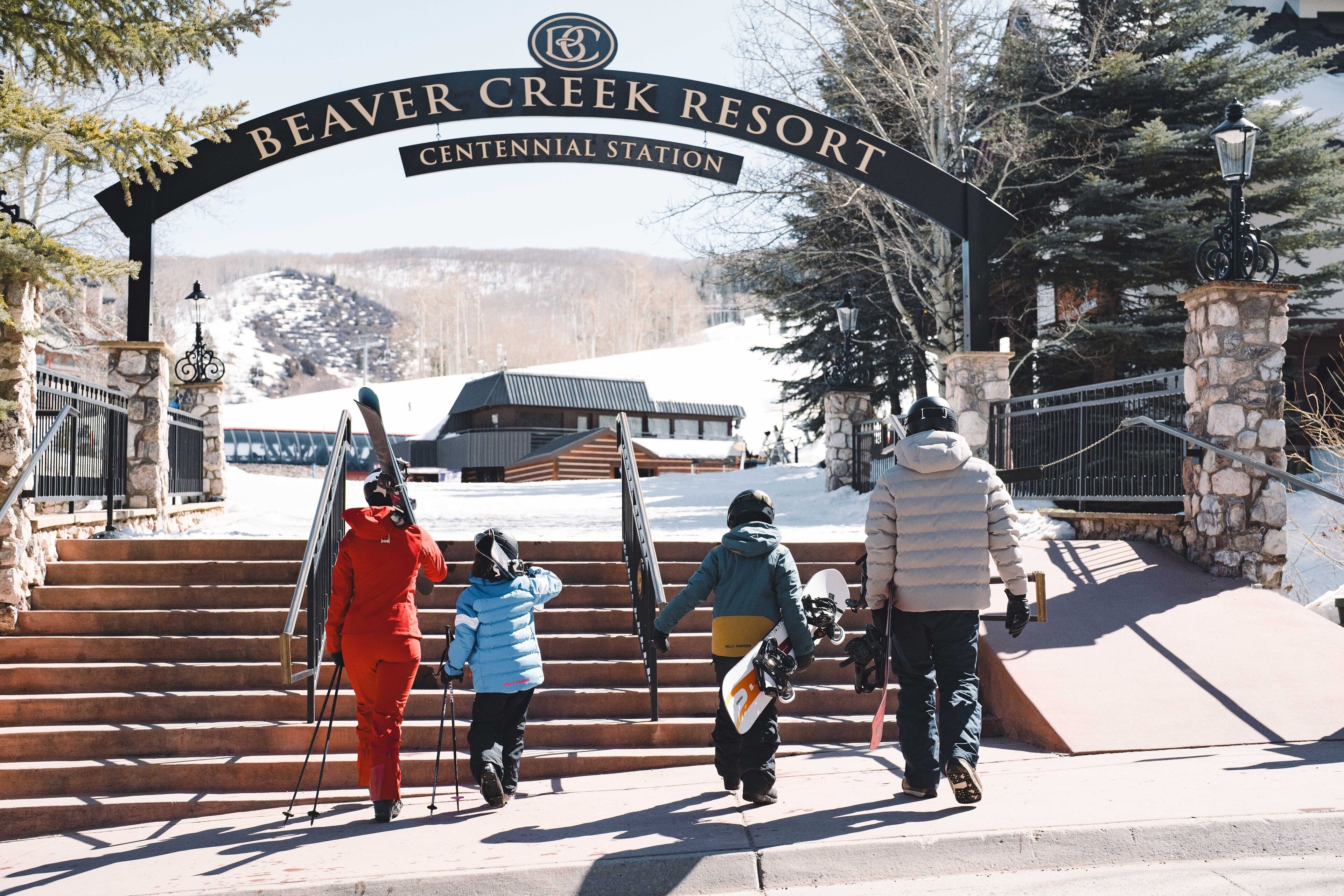L'entrée de la station de ski de Beaver Creek, avec une arche en pierre, des marches menant à un bâtiment et un paysage enneigé en arrière-plan.