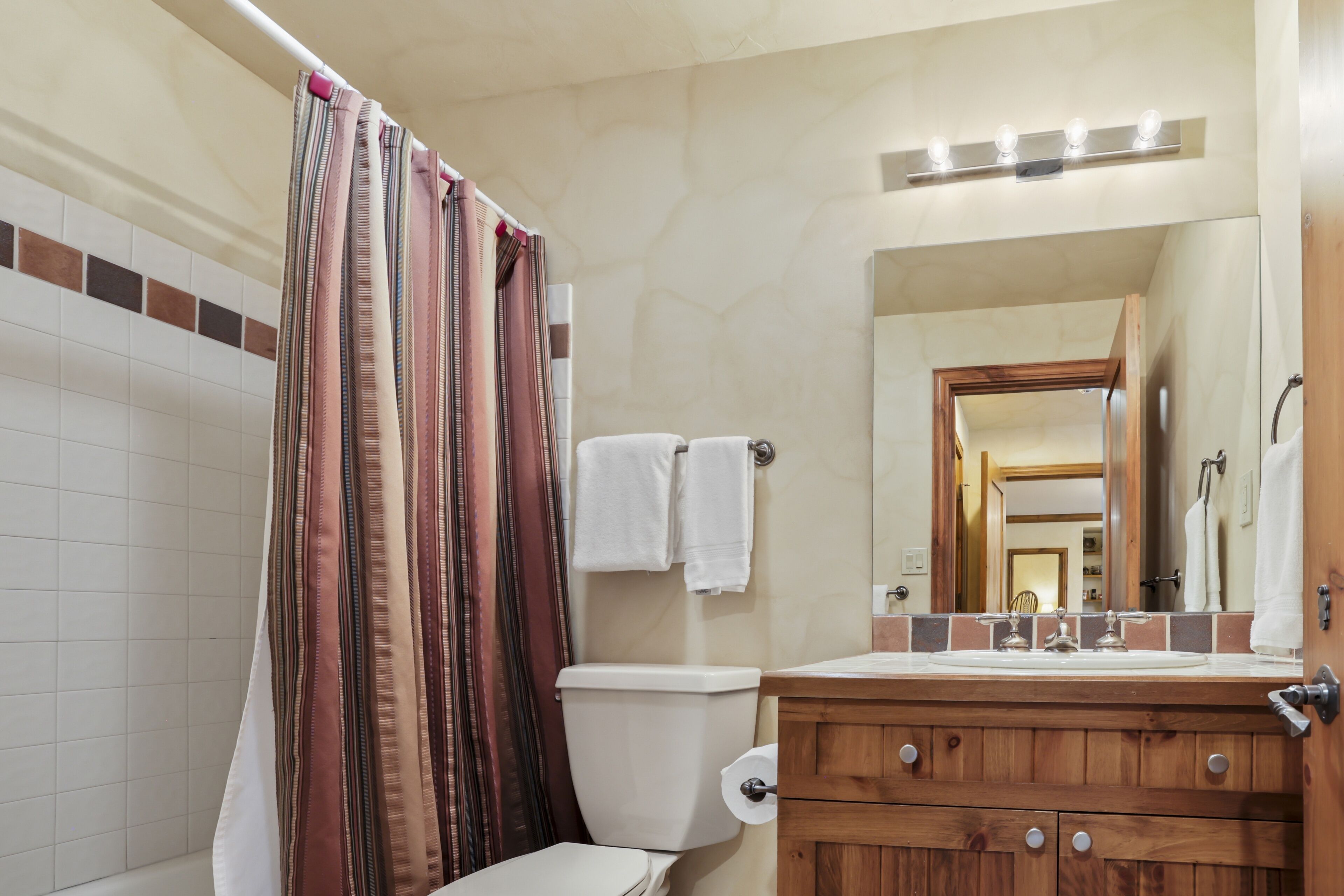 A bathroom with a toilet, a sink with a mirror, and a shower curtain.