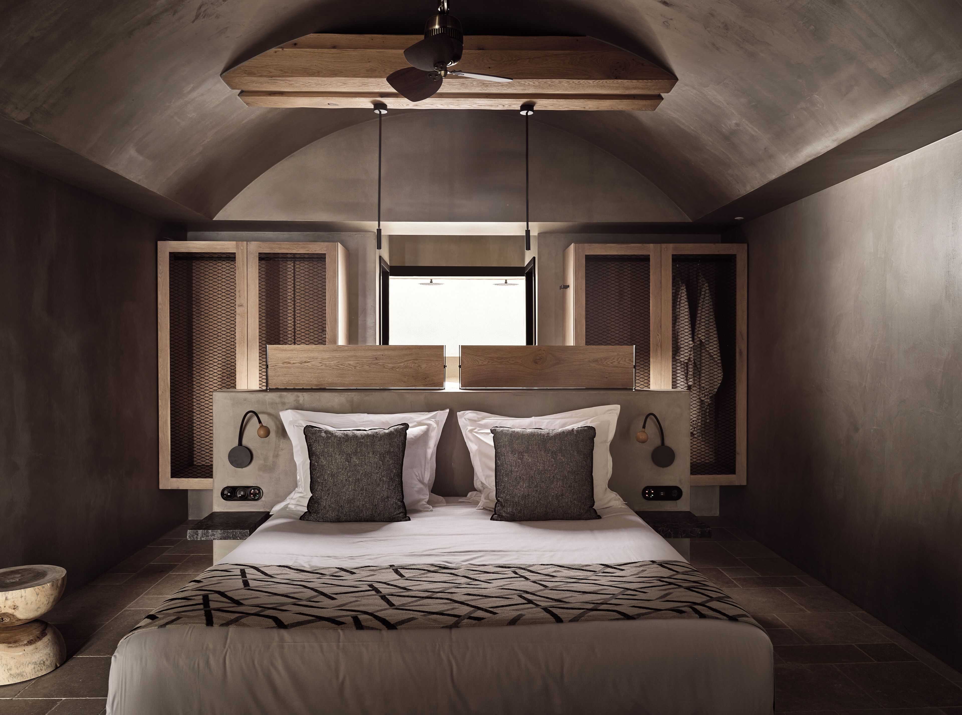 Une chambre moderne avec un grand lit, une tête de lit en bois et un ventilateur de plafond.