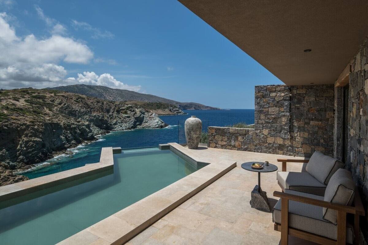 A pool with a view of the sea and rocky landscape.