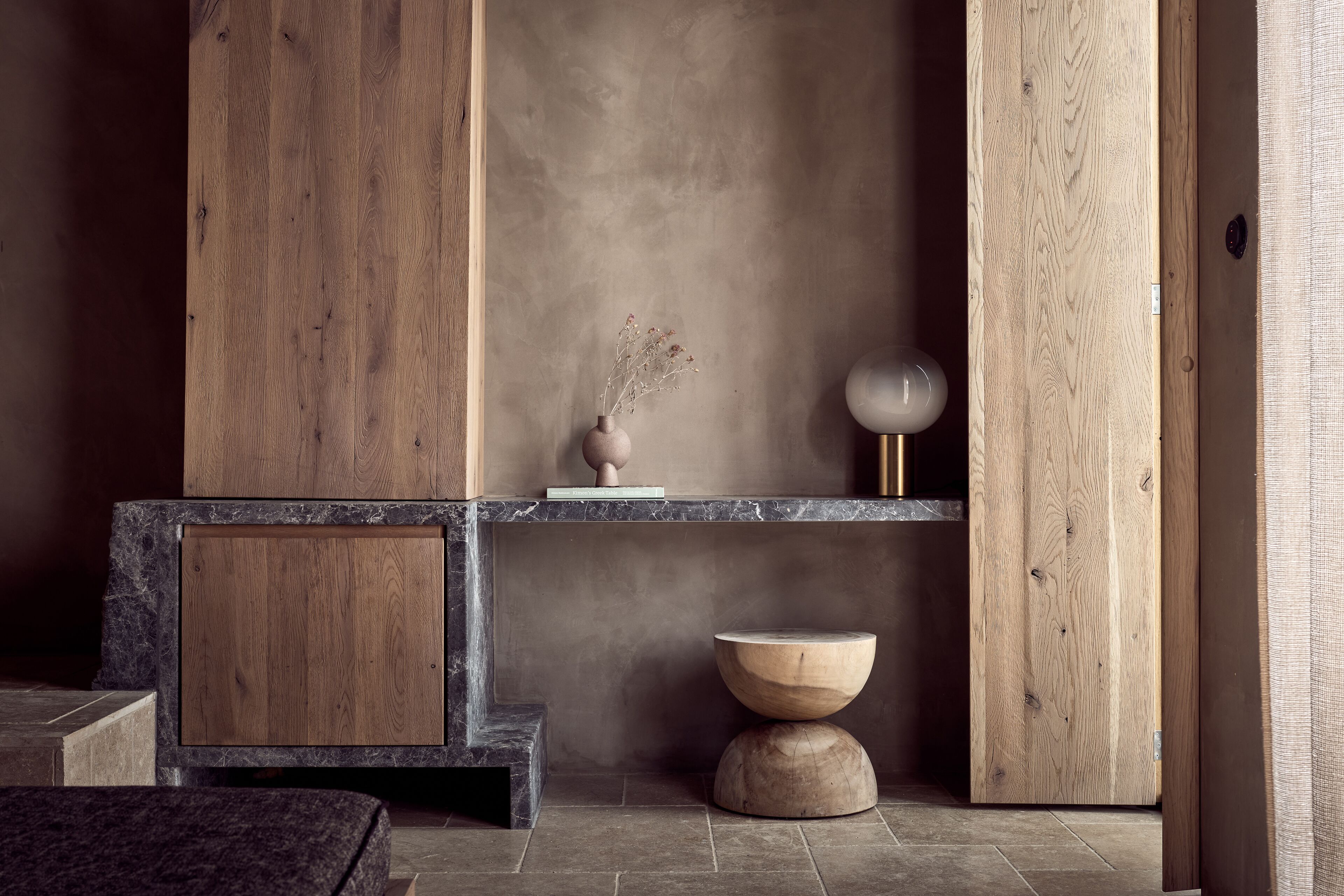 Un interno moderno con un mobile in legno, un vaso con fiori secchi e un tavolo rotondo.