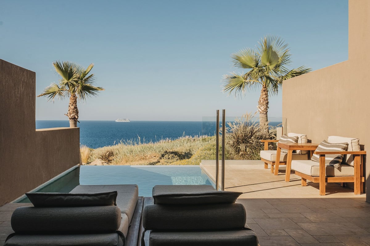 A poolside area with lounge chairs and a view of the sea.