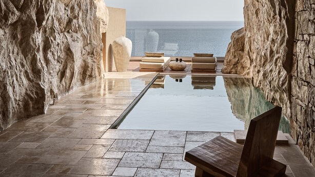 A modern infinity pool with a clear view of the sea, stone walls, and minimalist furniture. - Acro Wellness Suites - Adults Only (Malevizi)