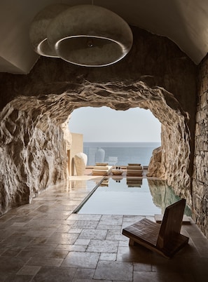 A modern infinity pool with a clear view of the sea, stone walls, and minimalist furniture. - Acro Wellness Suites - Adults Only (Malevizi)