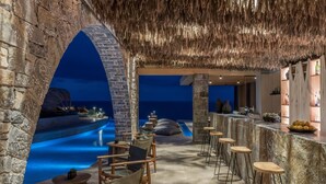 An indoor pool area with stone walls and a bar with stools. - Acro Wellness Suites - Adults Only (Malevizi)