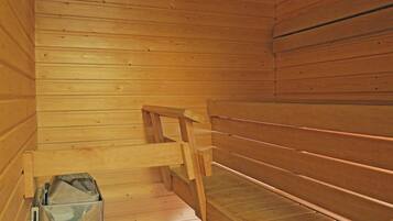 Een houten sauna met banken en een metalen bak.