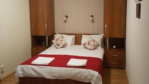 A bedroom with a wooden bed, two nightstands, a wardrobe, and a ceiling light. - Briza de Munte (Bran)