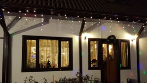 A house with a porch decorated with string lights, a small Christmas tree, and a door with a mirror. - Briza de Munte (Bran)