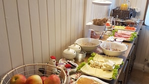 A buffet with various breakfast items including fruits, pancakes, and meats. - Briza de Munte (Bran)