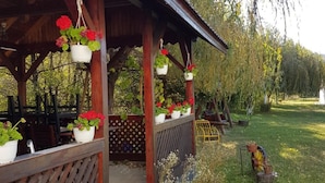 A wooden gazebo with hanging flower pots and a wooden deck. - Briza de Munte (Bran)