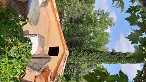 A terrace with wicker furniture and a view of trees and sky.