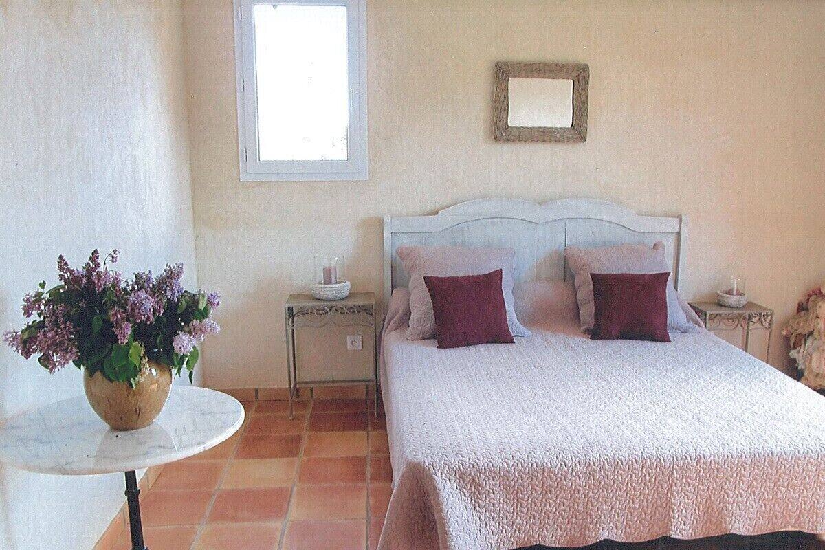 Een slaapkamer met een bed, nachtkastjes, een raam en een spiegel aan de muur.