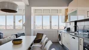 A modern kitchen with a dining area, large windows, and a city view. - Master Deco Gem in Graça (Lisboa)