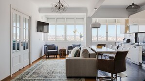 A modern living room with a large window, a dining area, and a kitchen. - Master Deco Gem in Graça (Lisboa)