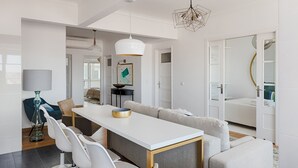 A modern dining area with a white table, grey upholstered chairs, and a geometric pendant light. - Master Deco Gem in Graça (Lisboa)