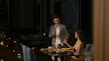 A dimly lit restaurant with a table set for two, featuring a wine glass and plates of food.