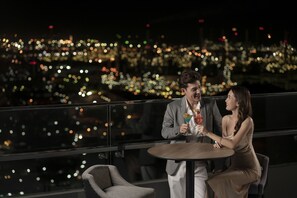 A couple seated at a round table with a cityscape view in the background. - Holiday Inn & Suites Siracha Laemchabang by IHG (Si Racha)