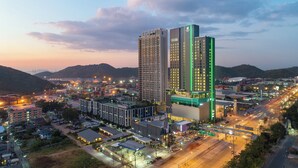 Un hotel di grandi dimensioni con numerosi piani, immerso in un panorama urbano con strade e altri edifici.