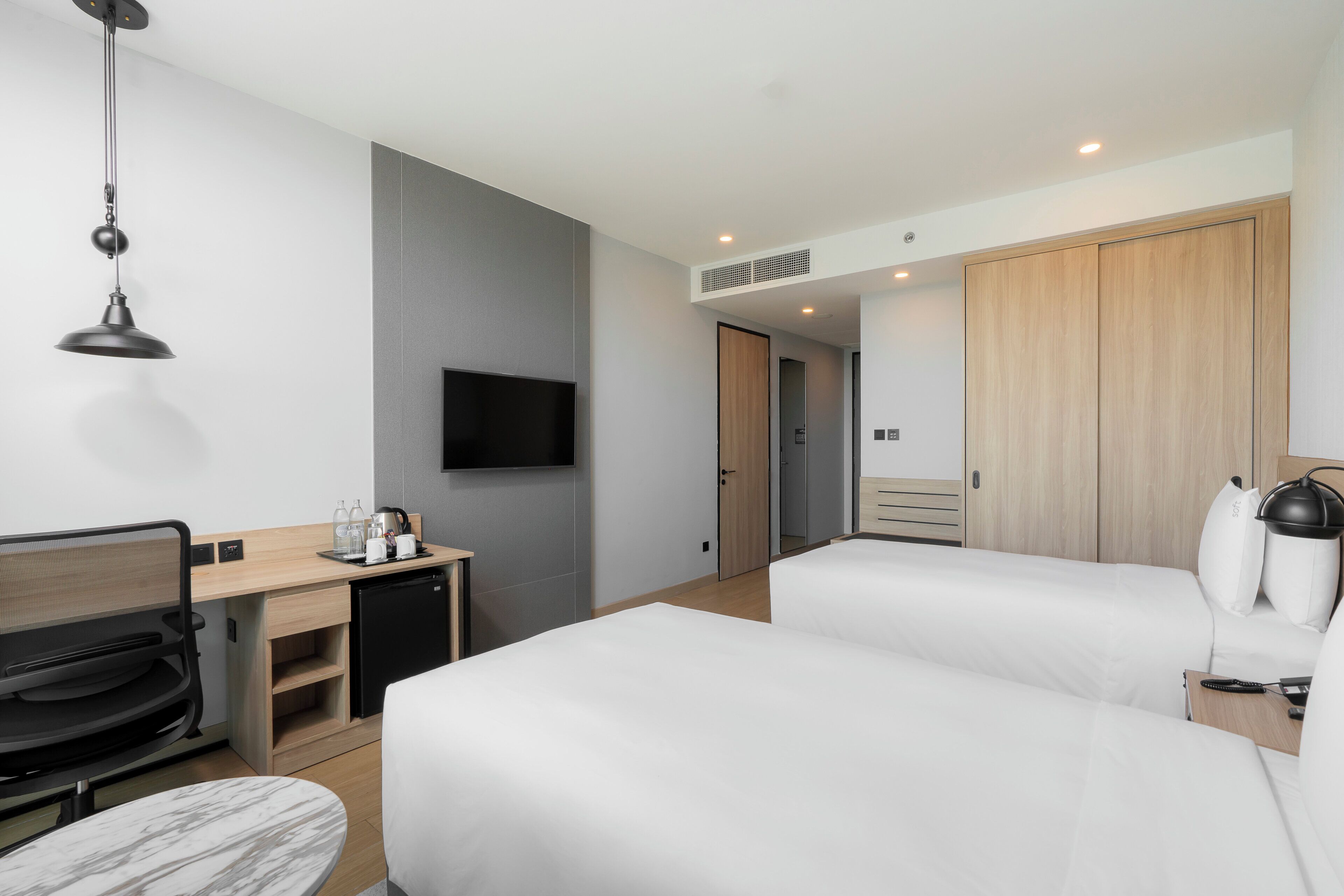 A hotel room with a bed, desk, chair, TV, and wardrobe.