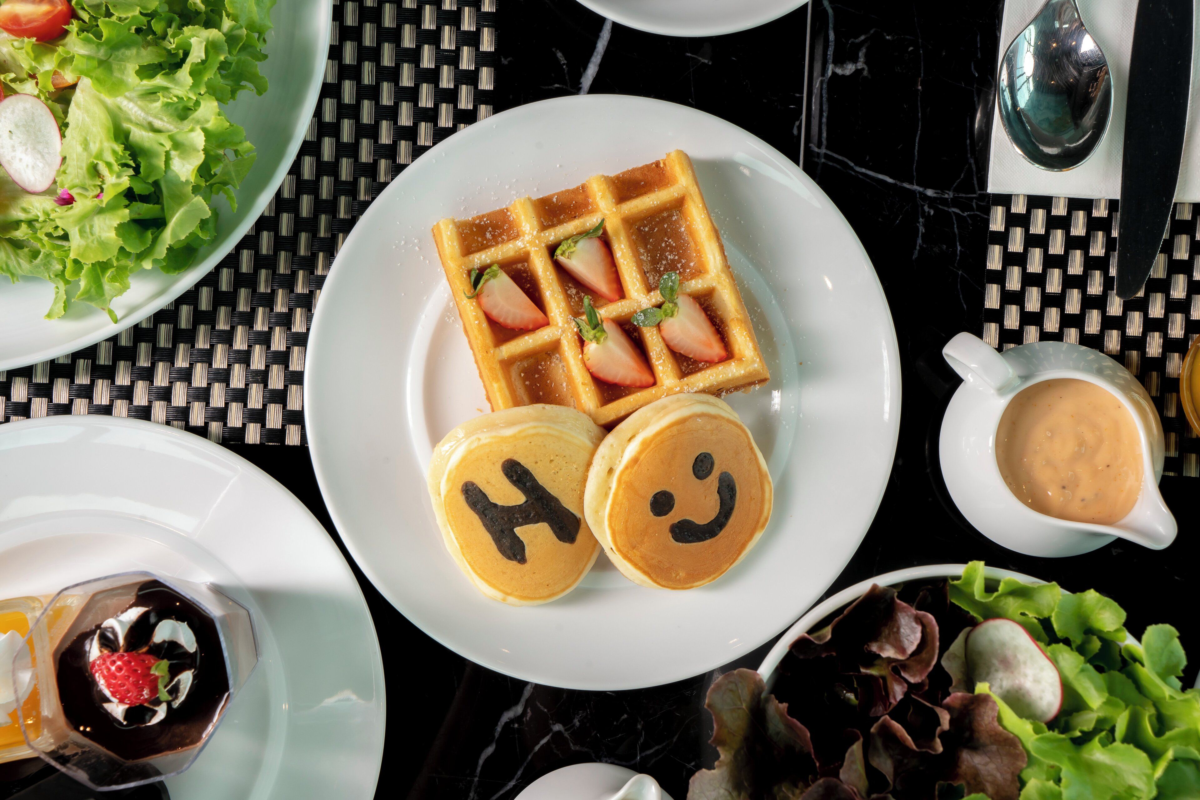 A breakfast setting with waffles, pancakes, and a salad.