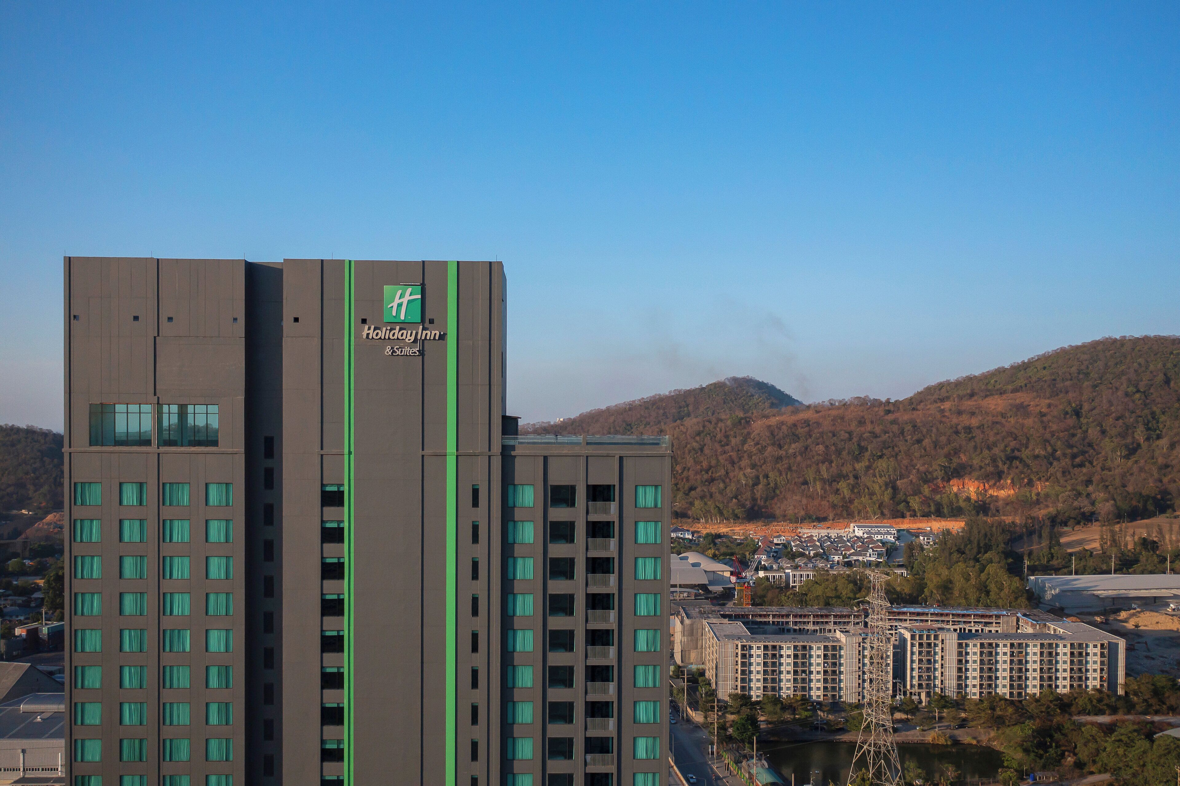 Un hotel Holiday Inn & Suites con un diseño moderno, que cuenta con varios pisos y un logotipo destacado.