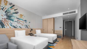 Ein modernes Hotelzimmer mit zwei Betten, einer Couch, einem Schreibtisch und einem großen abstrakten Wandbild.