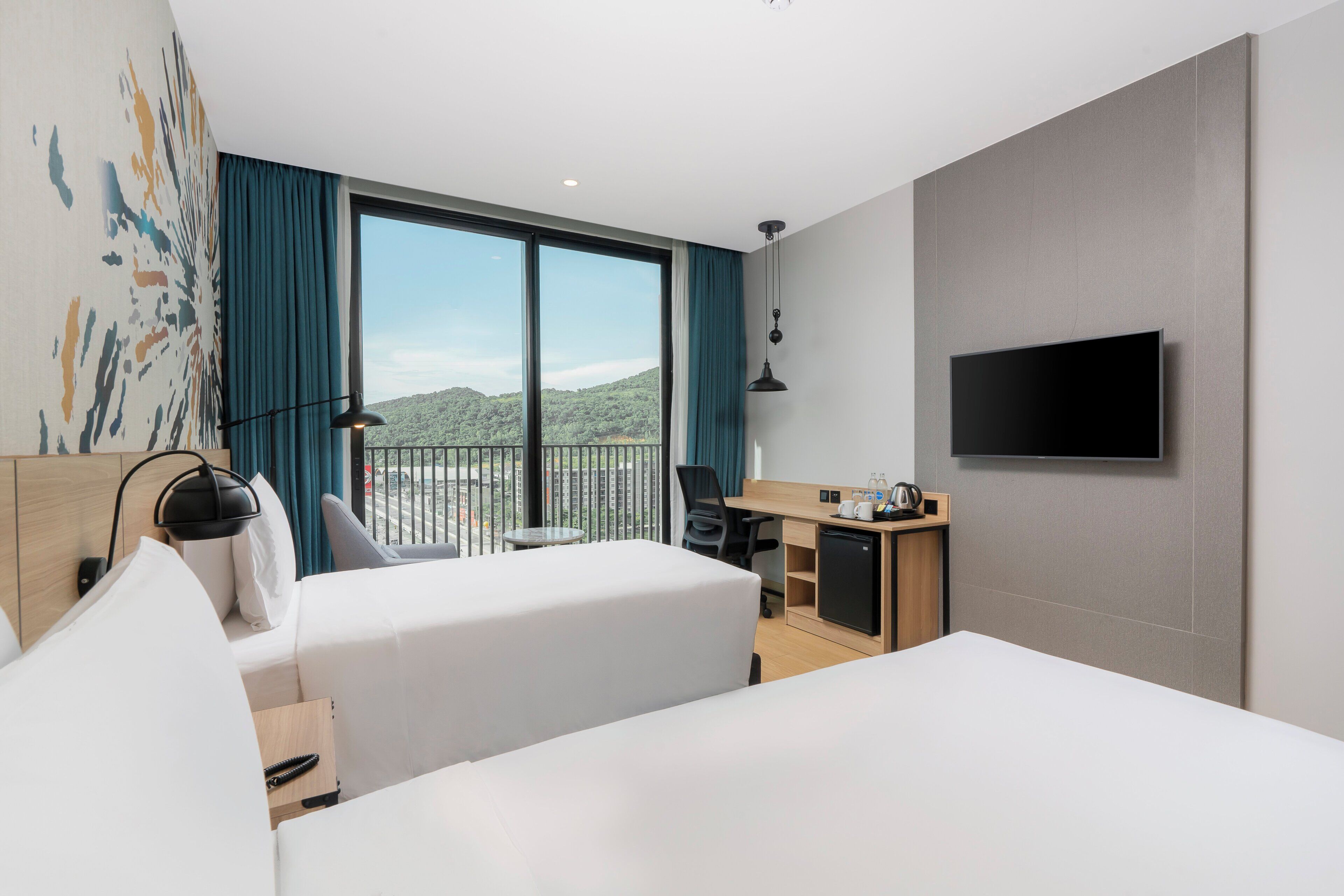 Une chambre d’hôtel dotée d’une grande fenêtre, d’un téléviseur à écran plat, d’un bureau et d’un lit.