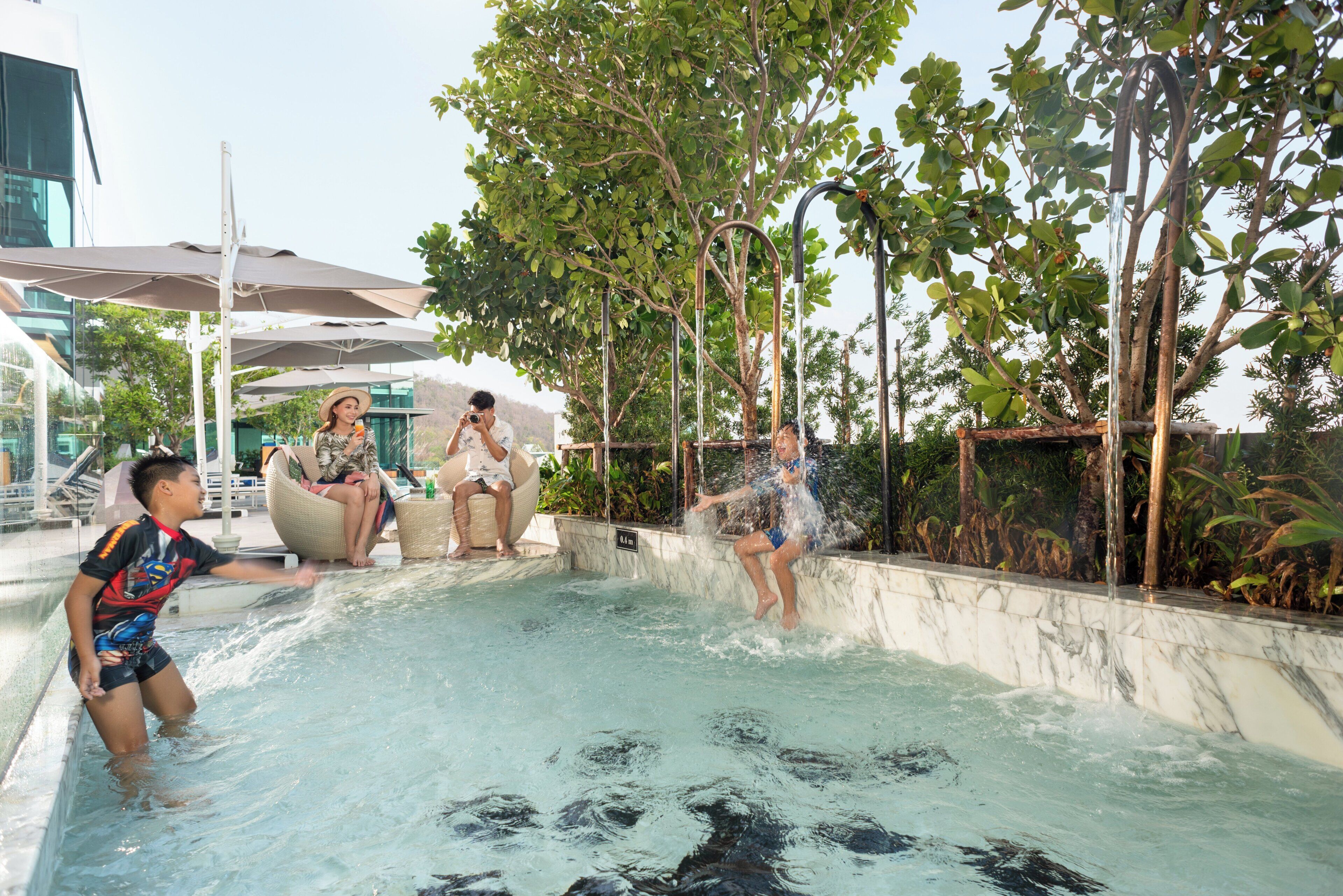 A water feature with a marble pool, surrounded by greenery and modern architecture.