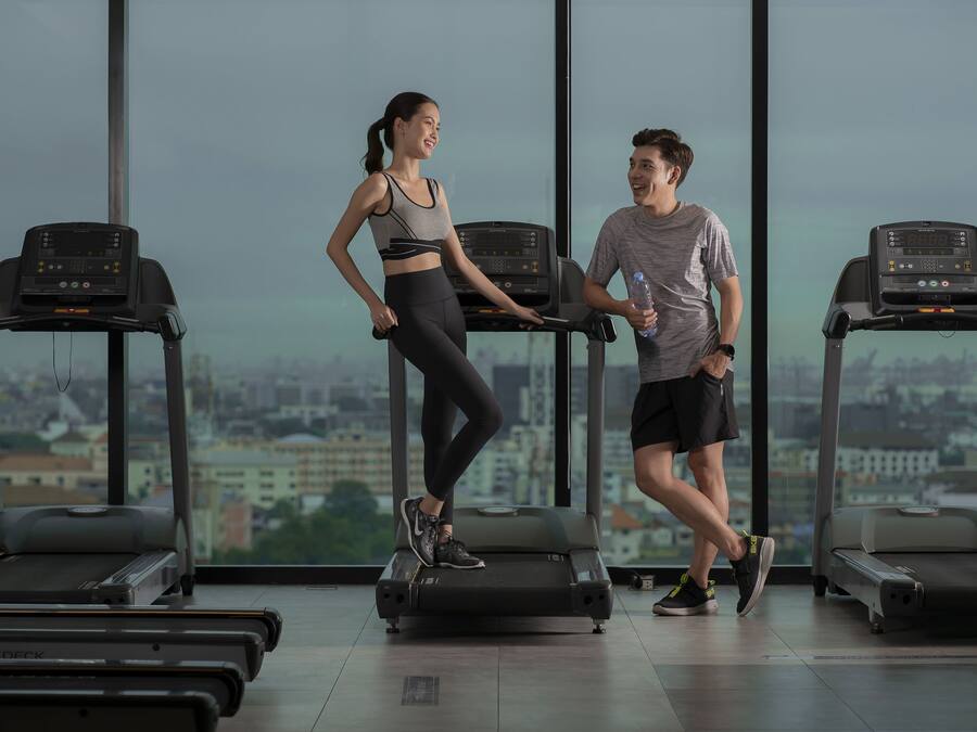 Un gimnasio con cintas de correr, vistas a la ciudad y un ventanal grande.